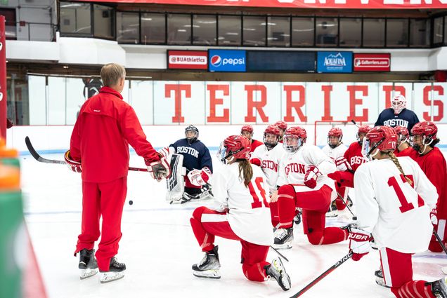 Brian Durocher, BU women’s hockey head coach, says his skaters “have been busy as all get-out, they have a good leadership group, and they're excited.” Photos by Olivia Fox/BU Athletics. Here Durocher stands in front of his team on the ice, who are kneeling.