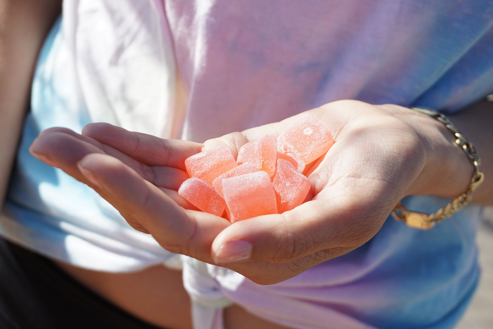 Photo: Closeup of a hand holding pink, sugary gummies.