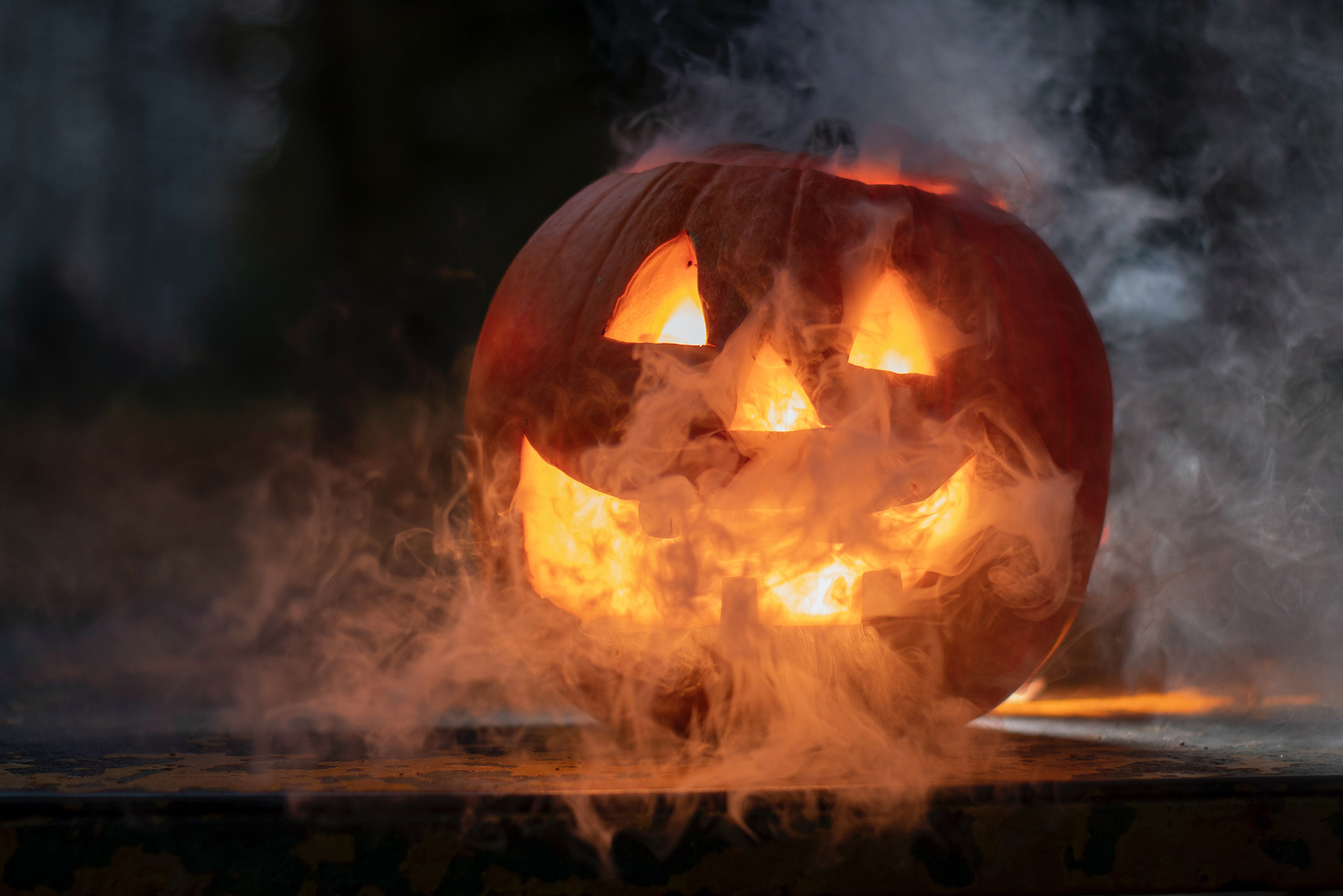 Photo: A smiling jack-o-lantern shown in a dark room. "Spooky" fog highlights the scene.