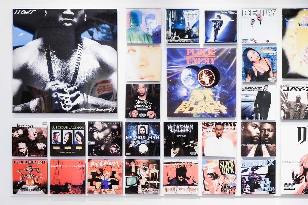 Photo: Gallery shot of Cey Adam's various album artwork. Various hip-hop album covers in varying sizes are displayed prominently on a gallery wall.