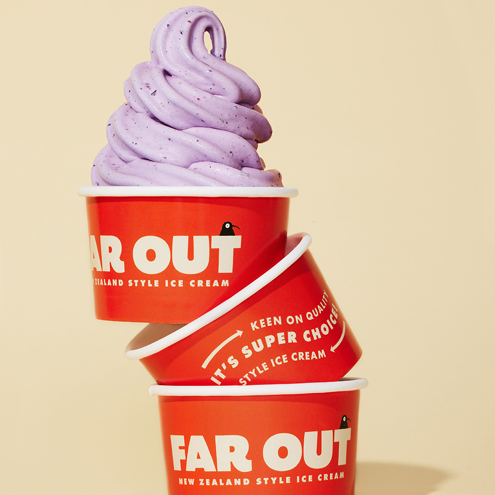 Photo of three, red ice cream cups stacked on top of each other. The topmost cip featured a large swirl of light purple ice cream. Red cups feature the Far Out Ice Cream logo.