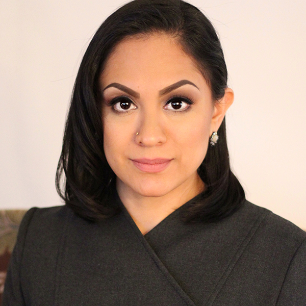 Photo of Maria C. Olivares. A tan woman with short black hair and wearing a black blouse poses for the camera.