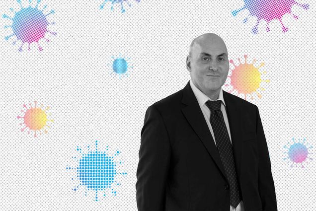 Black and white portrait of Drew Weissman (MED’87, GRS’87), smiling, in a black suit. A background with blue, purple, yellow and orange gradient coronavirus molecules are seen behind him.