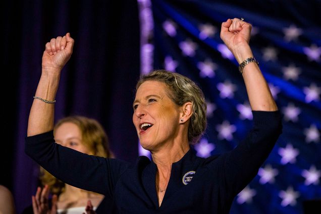 Photo: Republican Rep.-elect Jen Kiggans celebrates at her election party in Virginia Beach, Va., Tuesday, Nov. 8, 2022, after she defeated Rep. Elaine Luria, D-Va. A white woman with dirty blonde hair tied back is shown cheering with arms raised in front of a blurred American flag.