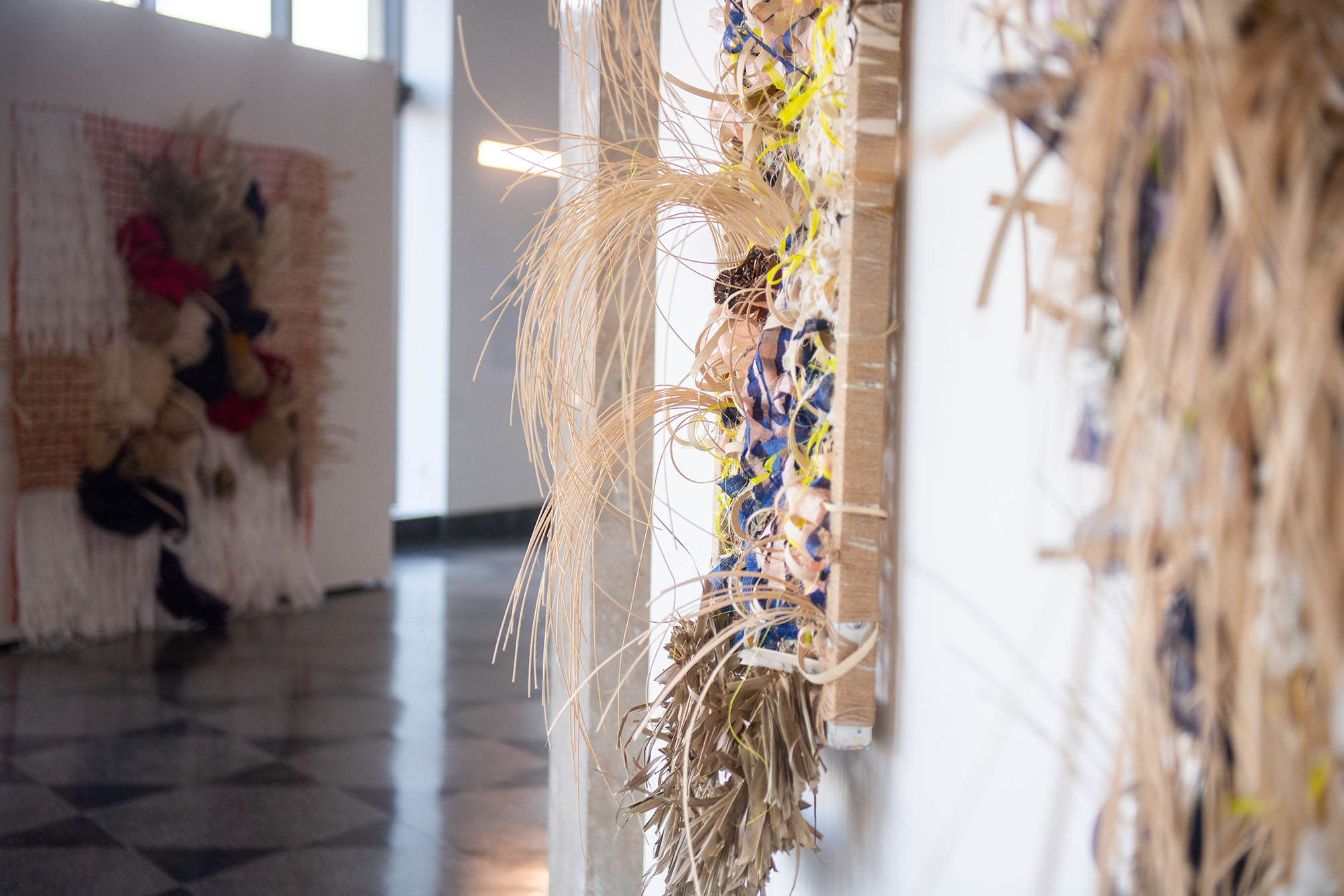 Photo: A shot of the 808 gallery with various large tapestries featured on the walls. The foreground focuses on one lively work and in the blurred background, other pieces can be sen as well.