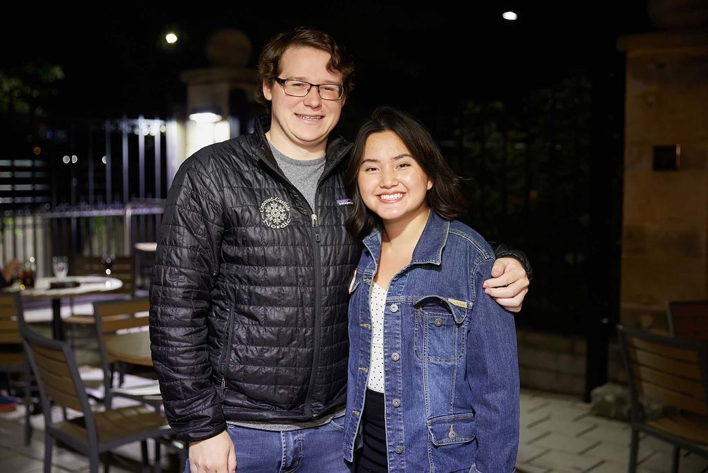 Photo taken of two young alumn during alumni weekend. At left, a young man with a black puffer jacket on, at right, a young women with a jean jacket on.