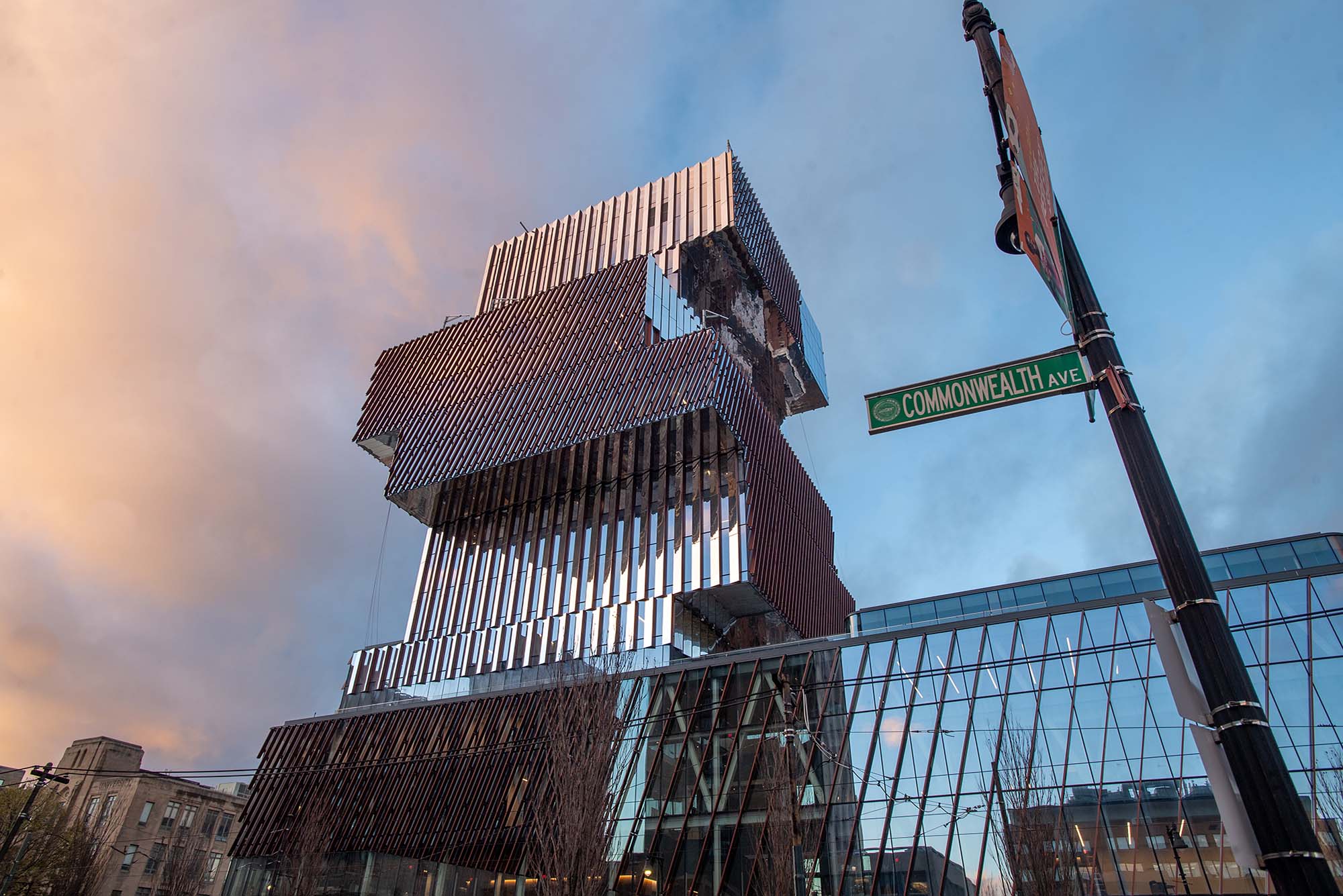 Photo: Center for Computing & Data Sciences at sundown Nov 16. A large, alternating bookcase-like structure is shown during a blue and red sunset. Structure is covered in reflective glass and reflects the street next to it.A green "Commonwealth Ave" street sign is shown prominently at the base of the building.