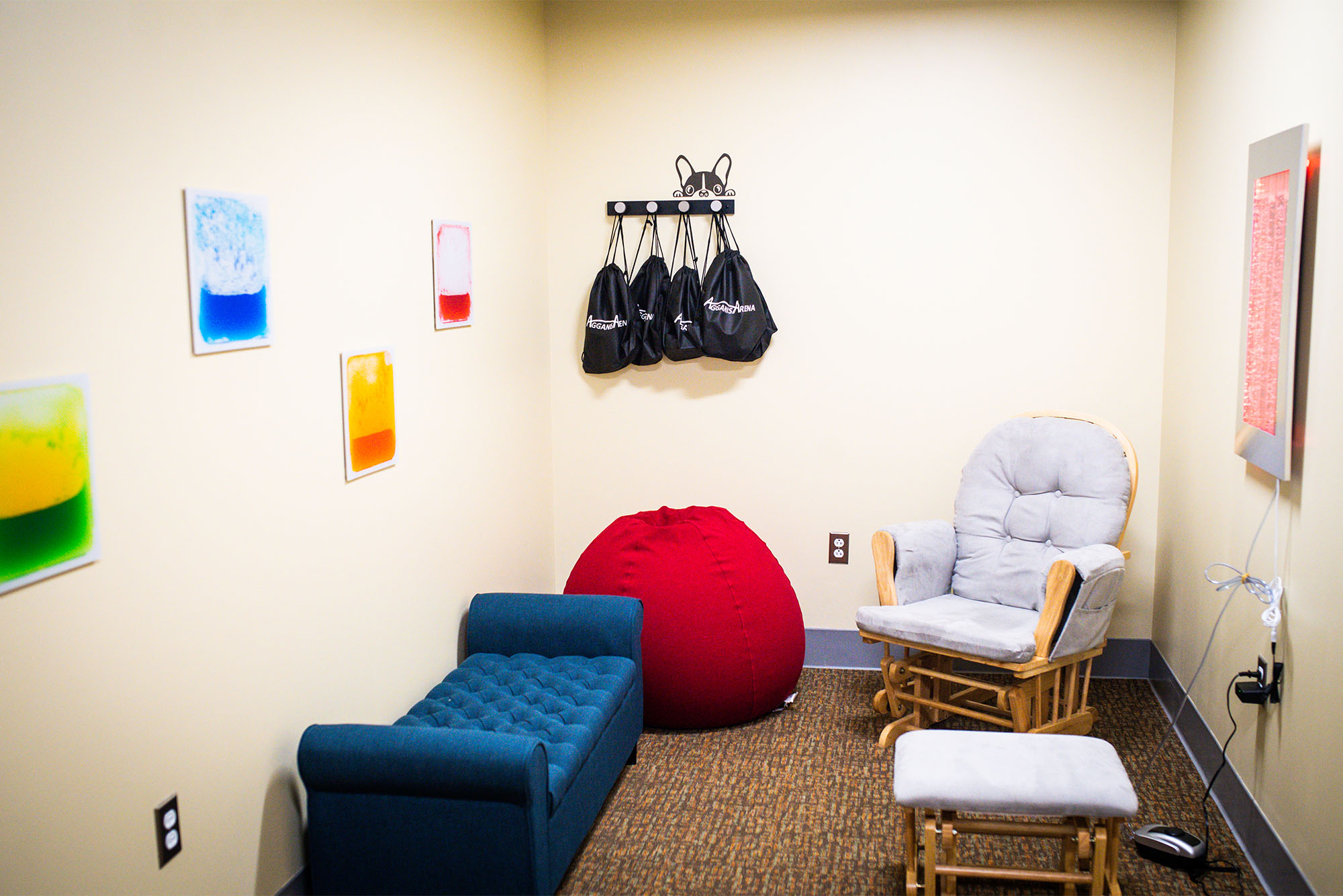 The Agganis Arena staff believes their new sensory room is the first of its kind at any sports or live event venue in the Greater Boston area. Photo by Jackie Ricciardi. Photo depicts a small room with beanbag chairs and other seating, with small trinkets and toys to play with as well as colorful art on the walls.