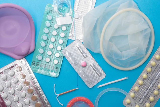 Photo: Overhead shot of a selection of reproductive health supplies including:pills, diaphragm, condoms, vaginal ring, IUD, implant, dmpa, emergency contraception, and contraceptive pills. All the supplies lie on a lie background.