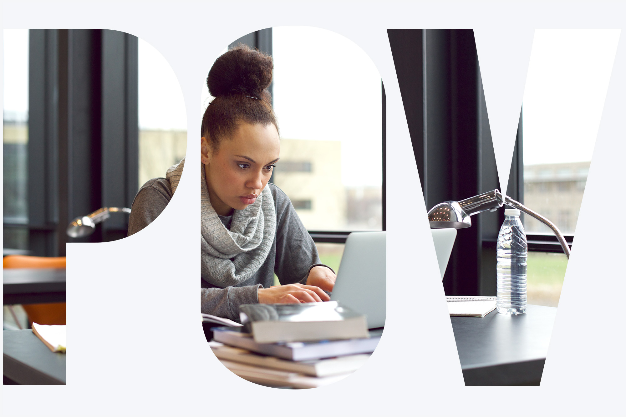 Image: Photo of a young Black girl sits in library, typing on laptop for her assignment. She has various books and notes open in front of her on the table as she looks to her screen in concentration. Photo seen through White overlay that reads "POV".