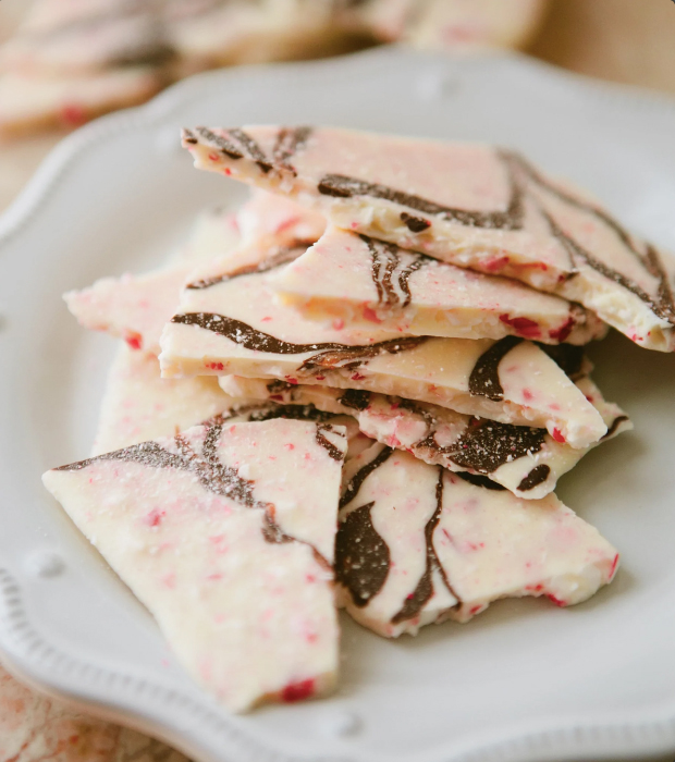 Photo: An assortment of peppermint candy bark on a white plate. White chocolate bark studded with peppermint and a drizzle of chocolate.