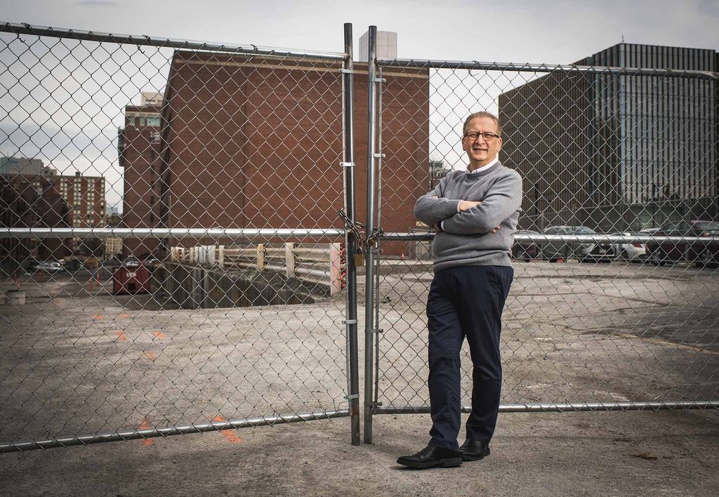 Portrait of Azer Bestavros who looks through a chain link fence towards the site of BU's new Data Sciences building.