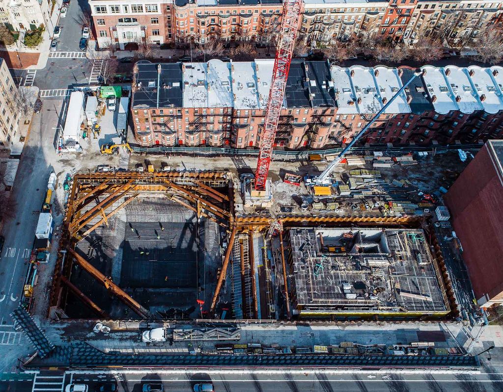 Photo: Drone coverage of the construction of the Center for Computing and Data Sciences building. Construction site of the future Center for Computing and Data Sciences building. A large pit filled with metal work, pipes, and foundation work is shown being built in progress by construction workers.