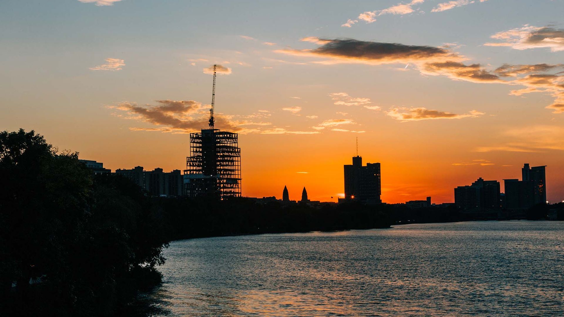 Photo: Construction of the Center for Computing & Data Sciences. The construction site is shown as a black silhouette on the shadowy Boston Skyline during a vibrant red and orange sunset.