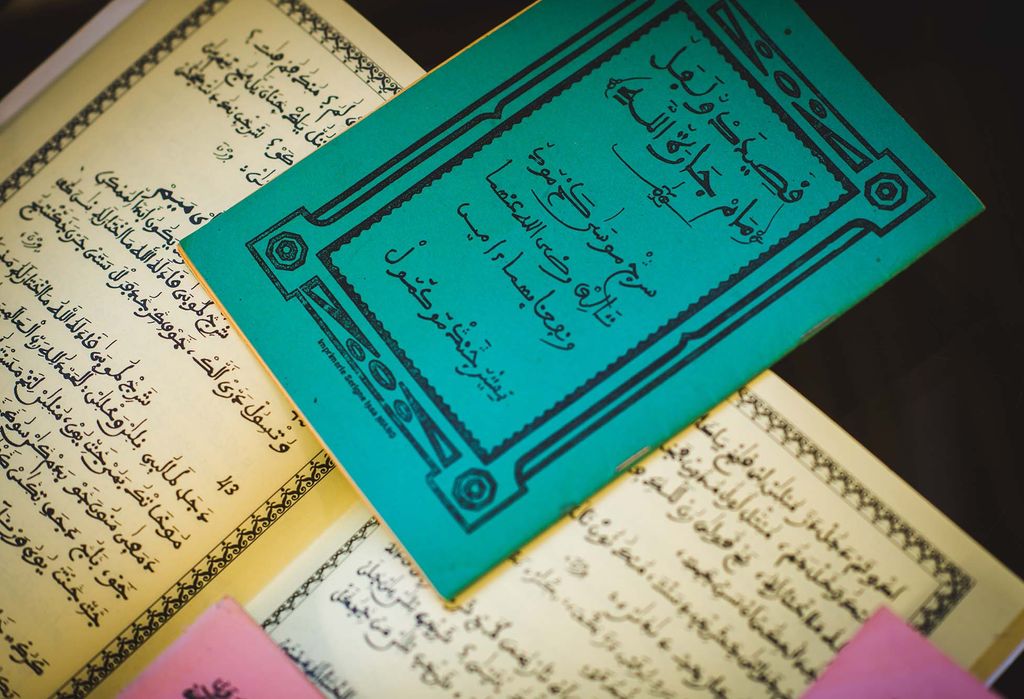 Photo: tan and blue books filled with, Ajami, a modified Arabic script, lay open on a table.