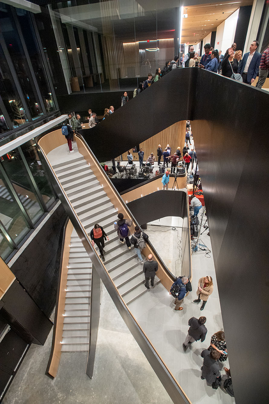 Photo: Various groups of people mill about a large, butterfly-style staircase as they tour a building.