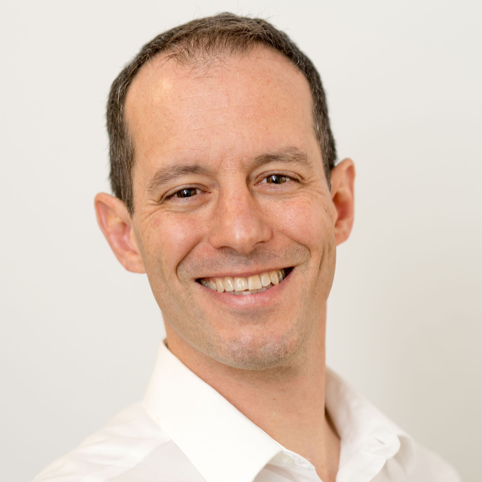 Adam Smith headshot in a white collared shirt