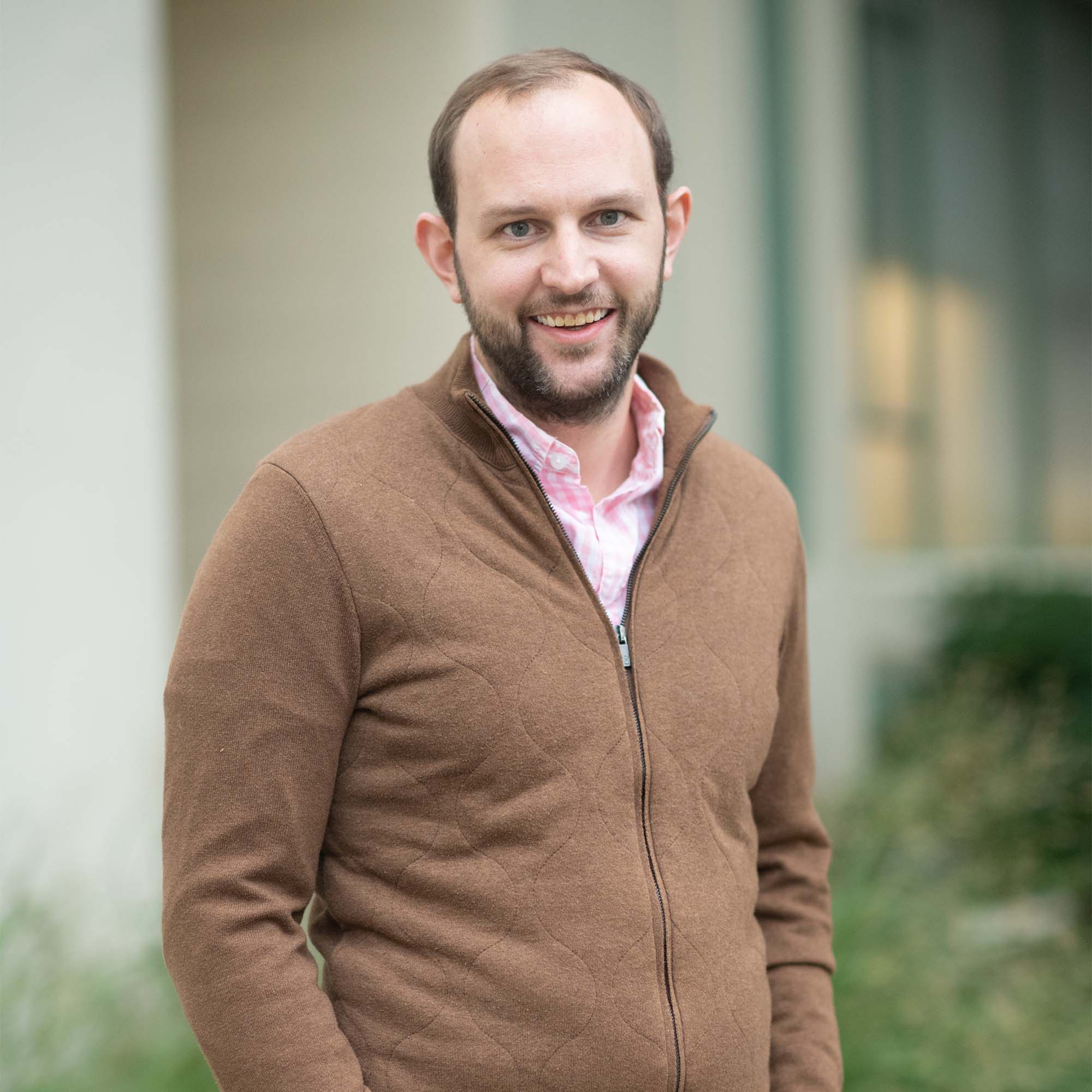 Portrait of Jonathan Huggins wearing a cardigan and smiling