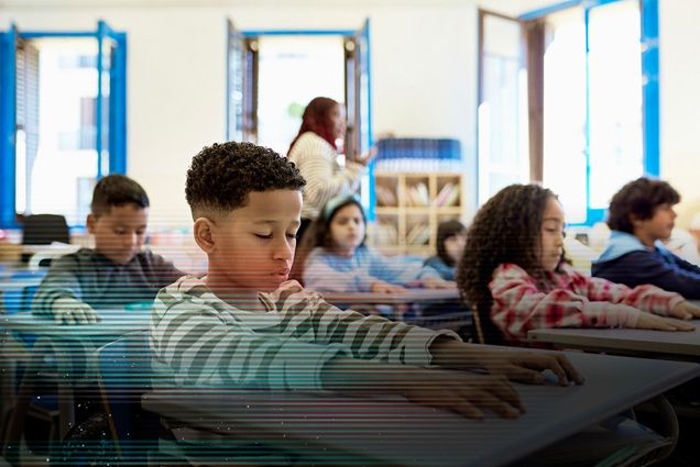 Photo: Waist-up view of young boys and girls sitting at child-size desks with eyes closed and arms relaxed during quiet time.