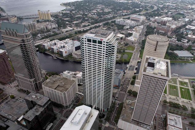 Photo: Aerial image of the city of Tampa, Fla. on Monday, Sept. 26, 2022. Tall skyscrapers and city buildings are shown from overhead on a cloudy, gloomy day. The city sits next to a large body of water.