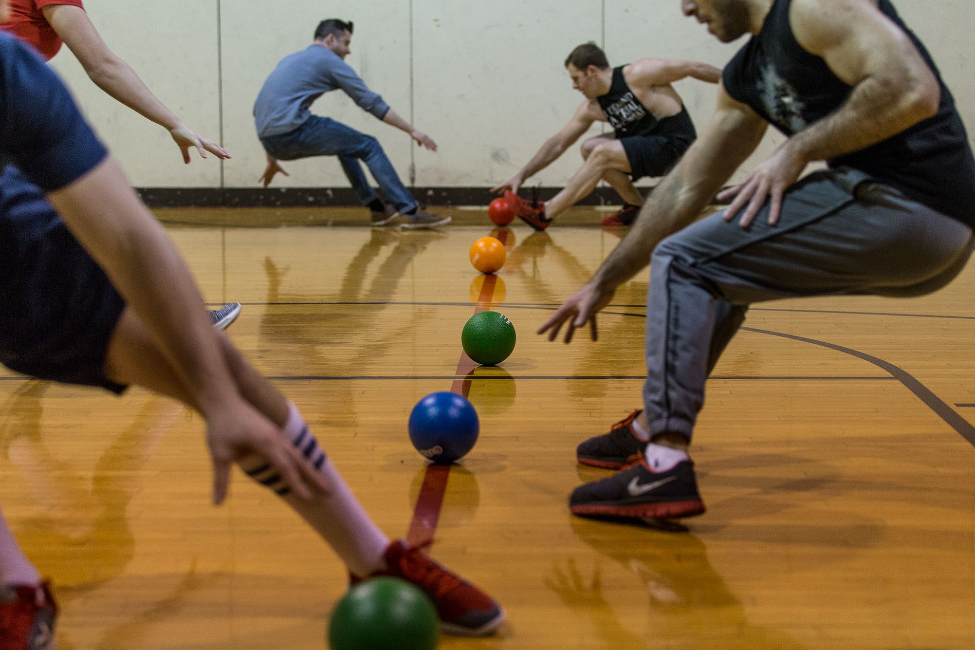 Photo: In a gymnasium, dodge balls line the court and players lunge to grab them.