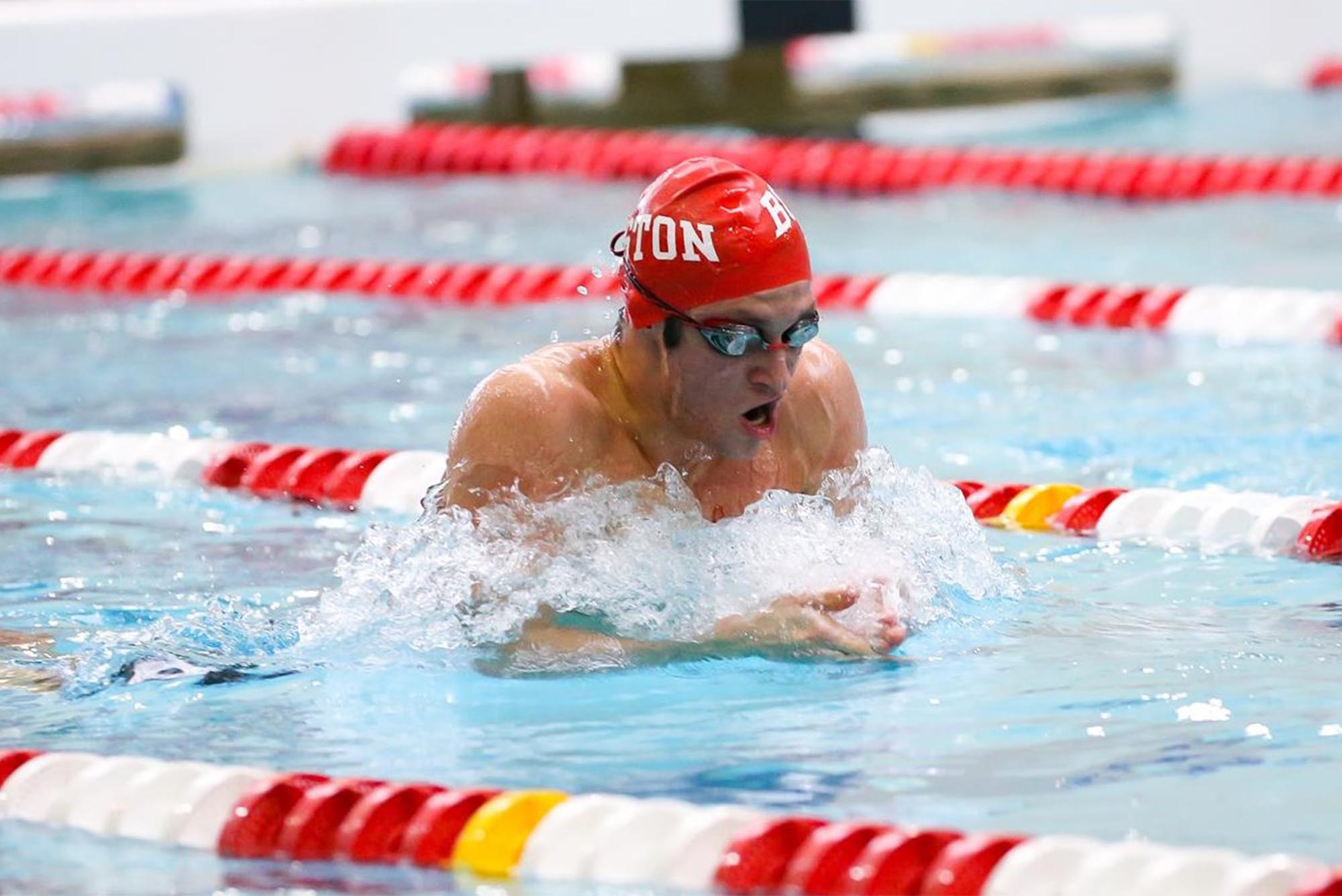 BU Men’s swimmer Jacob Lindner swims at a recent meet. He is wearing goggles and a BU swim cap.