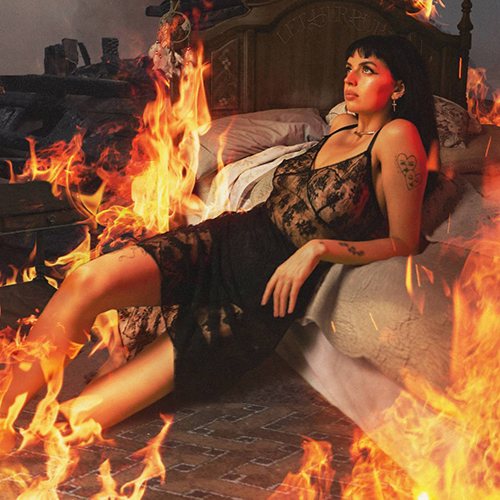 Image: cover art shows Rebecca Black, a white woman with black hair and a sheer white dress, lounging back against a bed as the room and bed around her are lit and burning with fire.