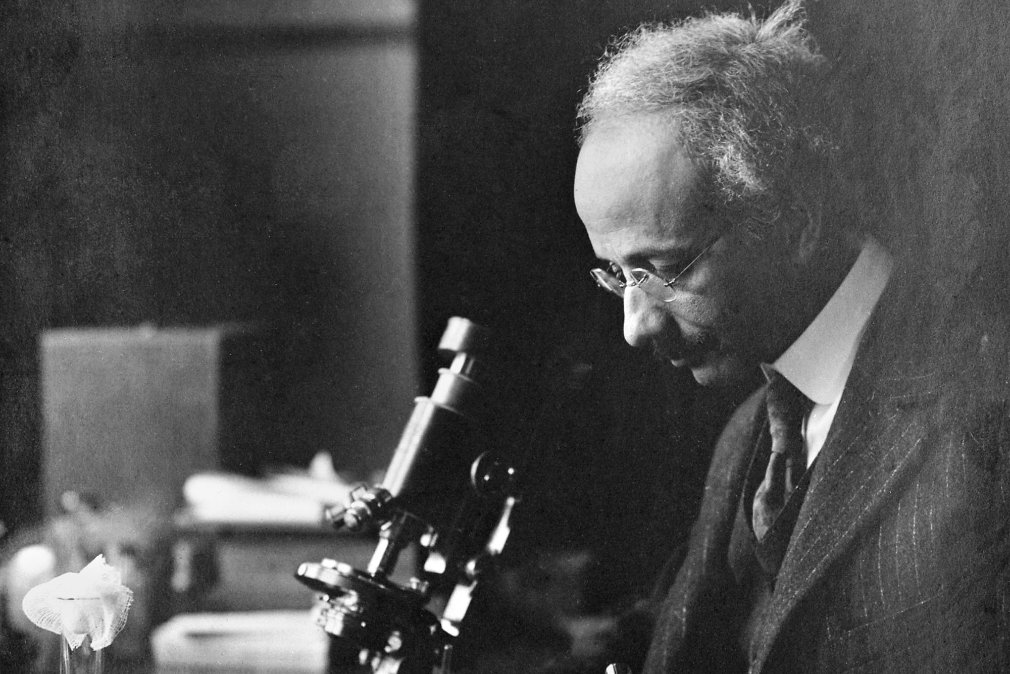 Photo: Black and white photo or Soloman Carter Fuller, the nation's first the nation’s first Black psychiatrist, looking into a microscope.