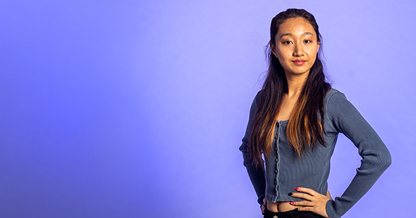 Photo: An Asian woman standing with her hands on her hips, smiling at the screen.