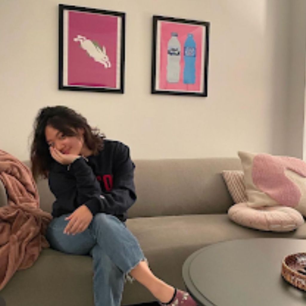 Student, Alexa Sudarto (COM'23), is sitting on a couch with her legs crossed and is smiling for a photo. 
Picture Credit: Alexa Sudarto (COM'23)