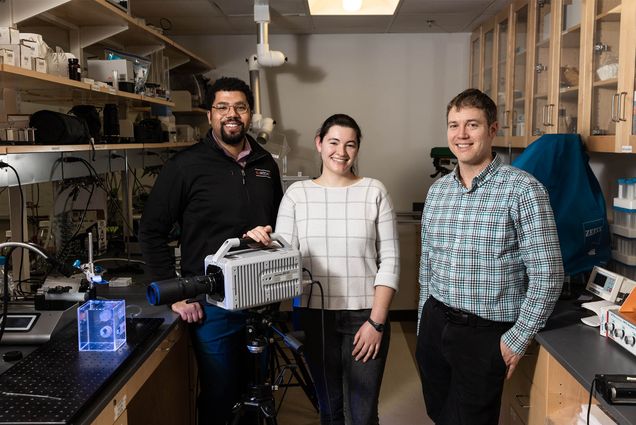 From left, Oliver McRae, Lena Dubitsky and James "Jacy" Bird, an ENG associate professor have been studying what bubbles can teach us about how microplastics, viruses, and bacteria aerosolize. Bird just put out a paper on his findings. The team worked in the lab, Wednesday, February 15, 2023. Photo by Jake Belcher. Three people stand in a lab setting with highspeed cameras and other technical equipment setup nearby.