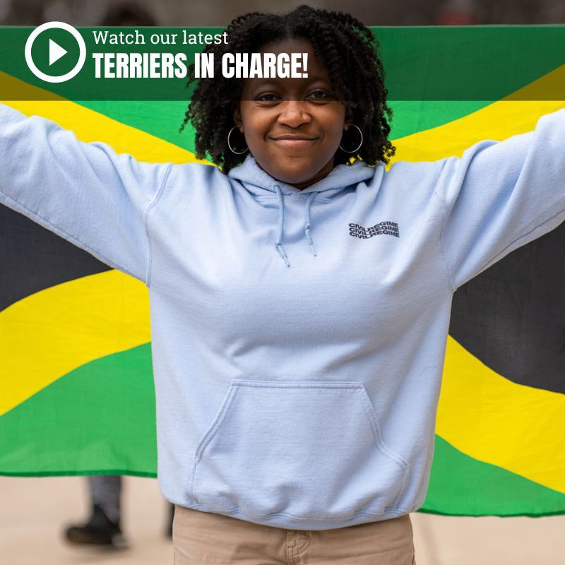 Photo: Brianna Bourne. a Black young woman with a kinky curly twist out smiles as she holds up a Jamaican flag. She wears a light blue hooded sweatshirt and tan pants as she holds up the flag behind her. Overlay reads 