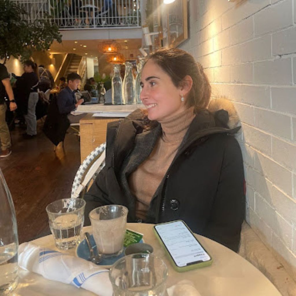 Student, Beatriz Iglesias, is at a restaurant with a jacket on, smiling off into the distance. 
Picture credit: Beatriz Iglesias (QST'23)