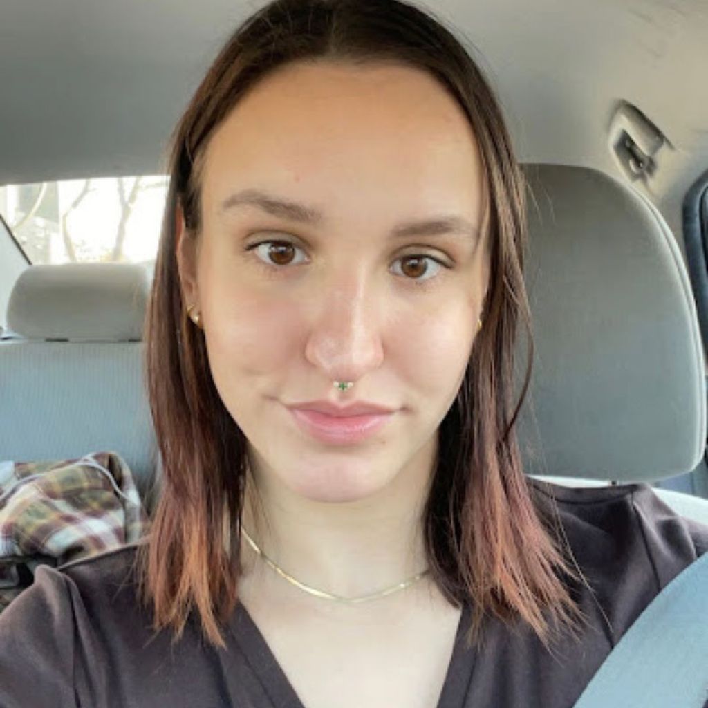 Student, Charlotte Bausha, takes a photo of herself in the front seat of a car. She is smiling softly. 
Picture credit: Charlotte Bausha (CAS'23)