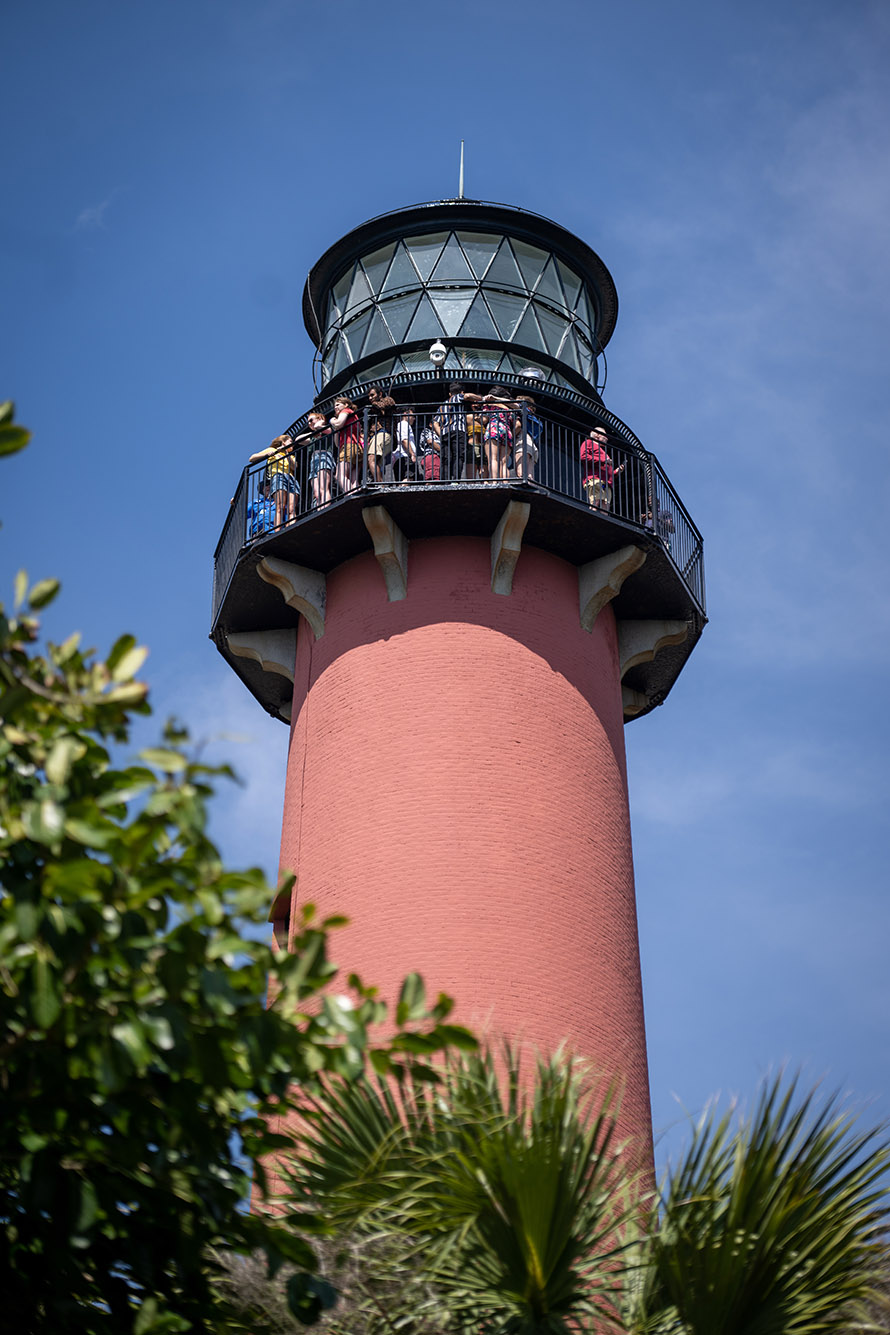 Photo: A light red lighthouse is shown during a brightly lit day.