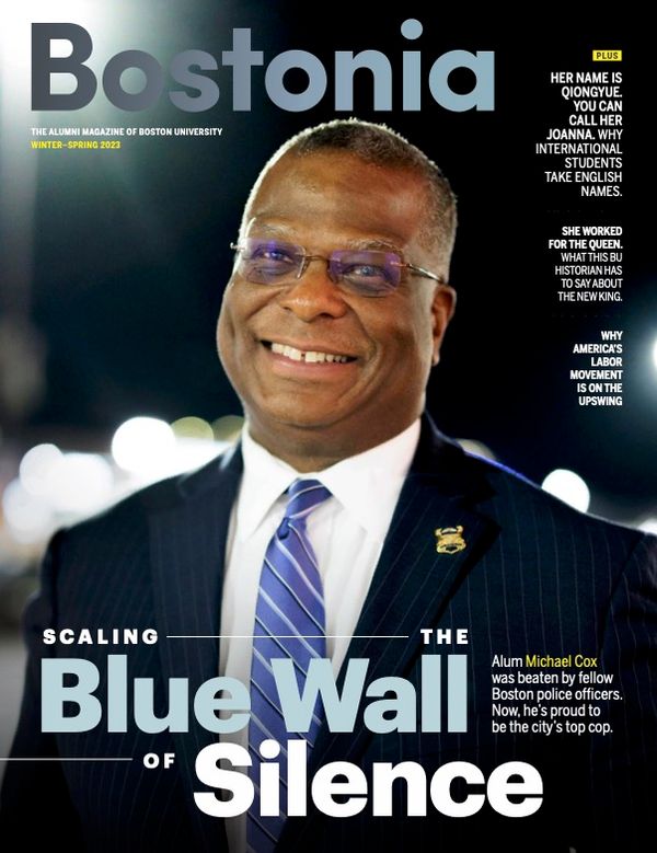 Image: cover of the Bostonia magazine winter-Spring 2023 issue. A photo of Boston Commissioner Michael Cox is shown on the right. Photo of Boston police commissioner Michael is front and center. A Black man wearing glasses, a navy blue suit and blue striped tie, smiles as he looks to the distant left. Large text reads "Bostonia, Scaling the Blue Wall of Silence" and features the headlines of other features images to the lower righthand side in smaller font.