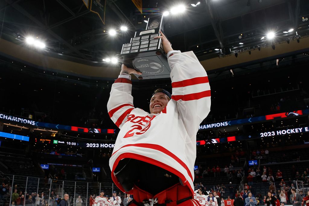 Photo: BU Hockey player holds up trophy in celebration after winning 10th title.