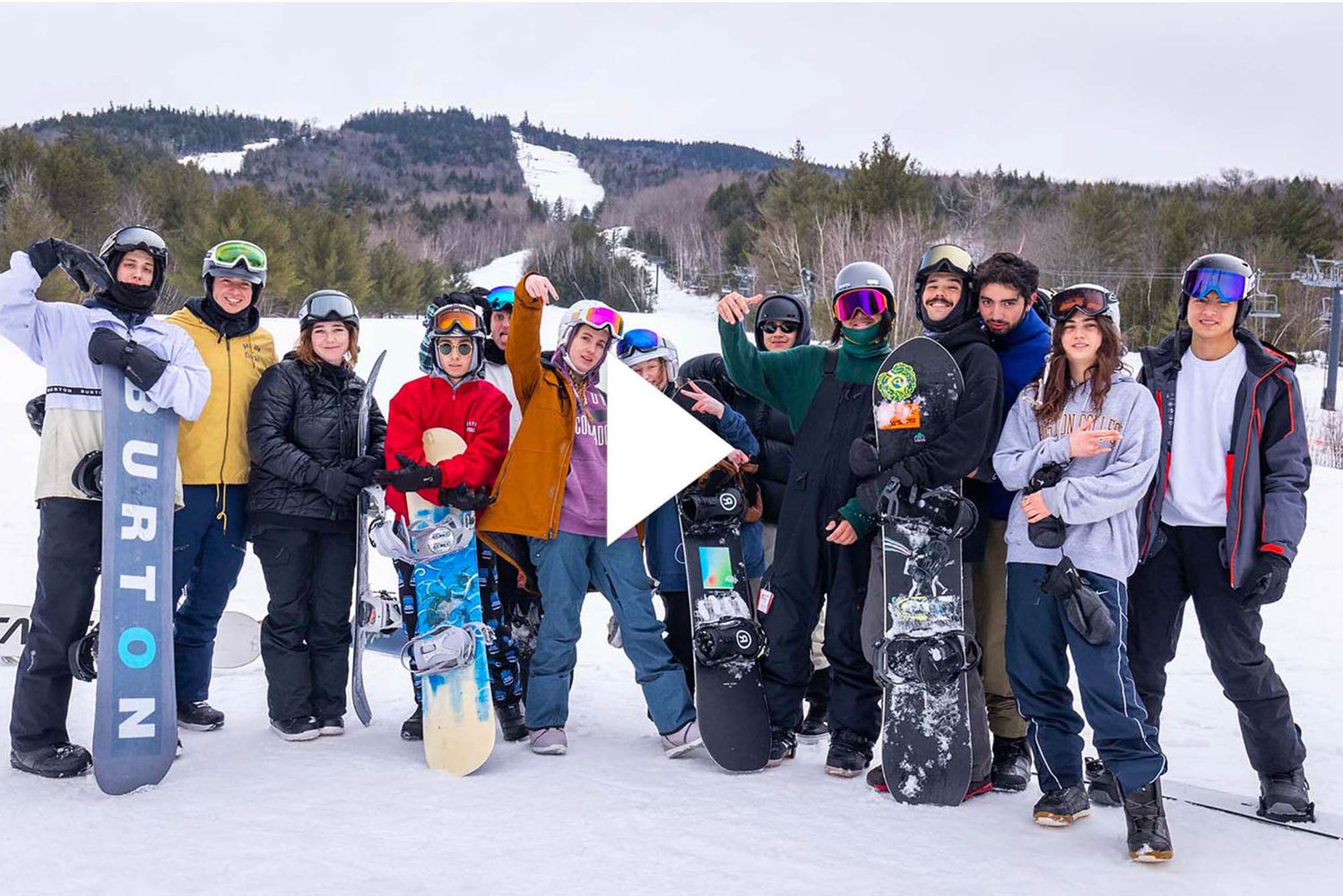 Photo: A panned shot of the entire BU snowboarding team on a snow slope. They are all in their personal gear and warm clothes.