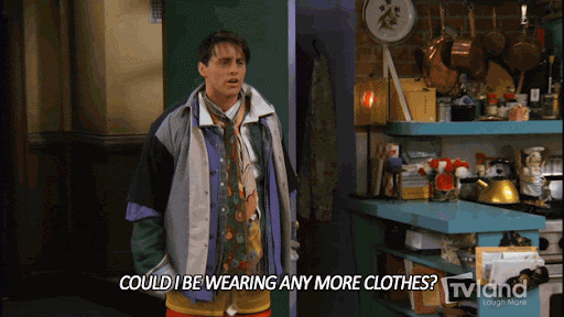 This is a GIF from the popular TV show 'Friends', where one of the characters has multiple layers of clothing on. He is in an apartment is dramatically expressing the sentence "could I be wearing anymore clothes?" He throws his hand to the side and widens his eyes and shakes his head for dramatic effect. The GIF has a closed caption, with the question he is asking in the GIF, which is "Could I be wearing any more clothes?"