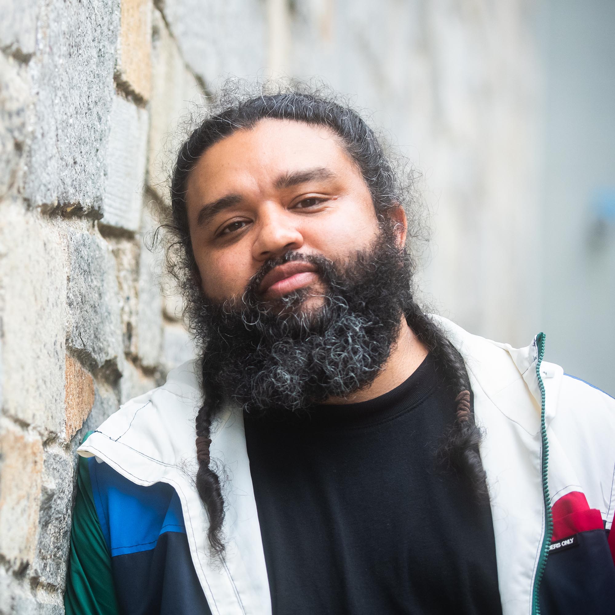 Photo: New director, Nathan Alan Davis, a man with a large black beard wearing a jacket, poses for a headshot portrait