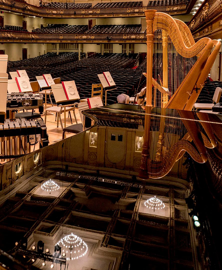A rare snapshot of Symphony Hall (with empty seats) taken from the stage. The perspective is shown from behind a Grand Piano and the lighting is a warm vanilla. All instruments and playbooks are mounted and ready for their performers. Photo: Marco Borggreve.