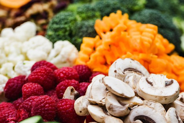 Photo: A zoomed photo of various different vegetables such as mushrooms, carrots, cauliflower, and a handful of raspberries on the lefthand side.