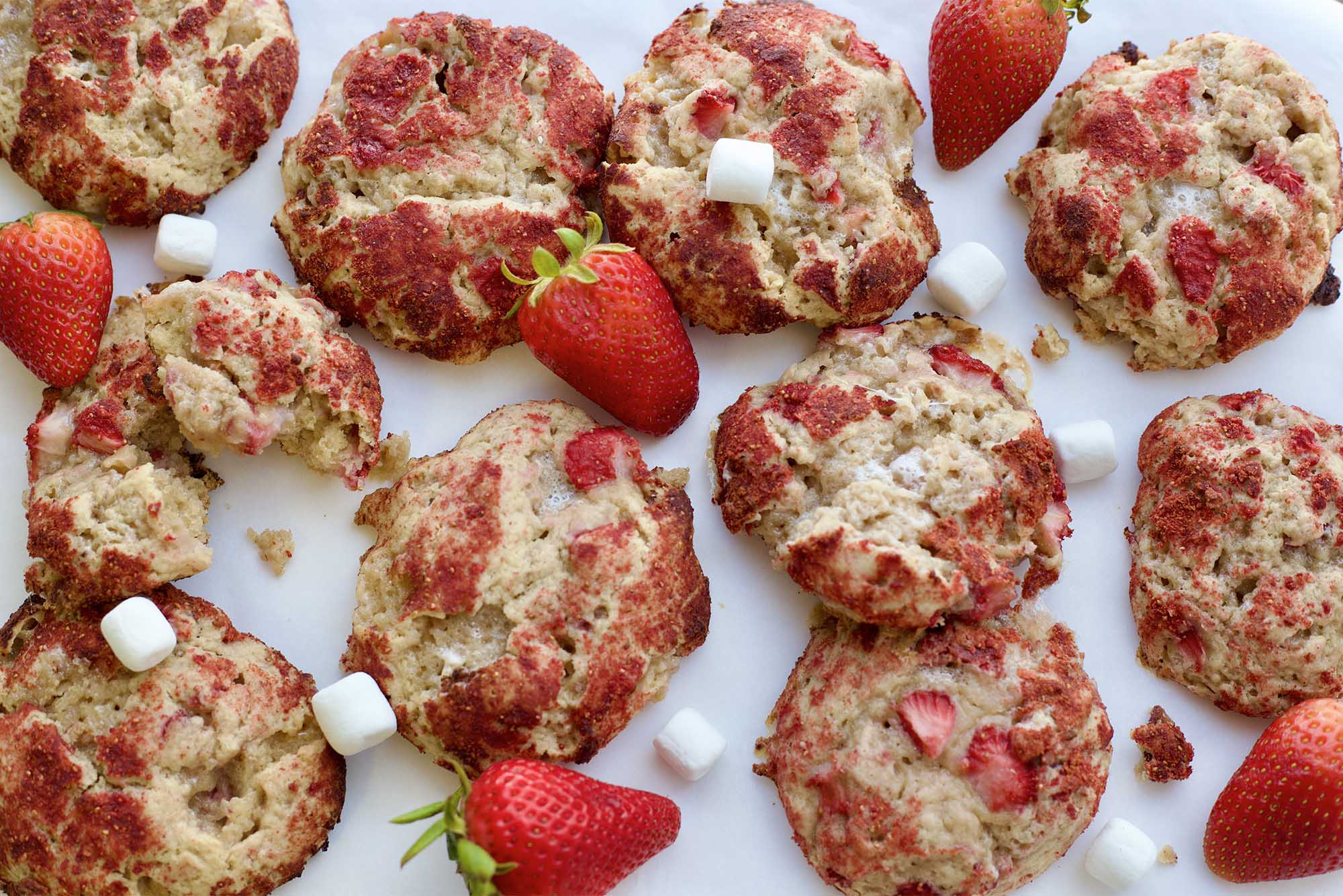 Photo: a dozen or more strawberry shortcake cookies, which are golden brown and have strawberries and minimarshmellows around the sides