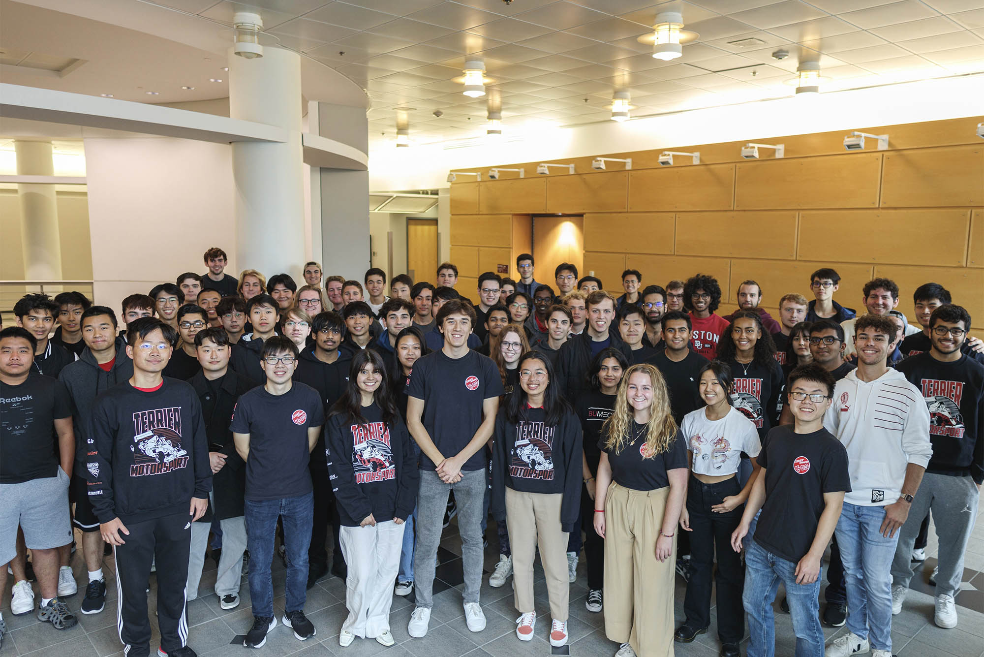 Photo: A large group of students from Terrier Motorsport. They are all wearing casual clothing, like jeans and t shirts, and smiling at the camera. The group appears to be around 50-60 students.
