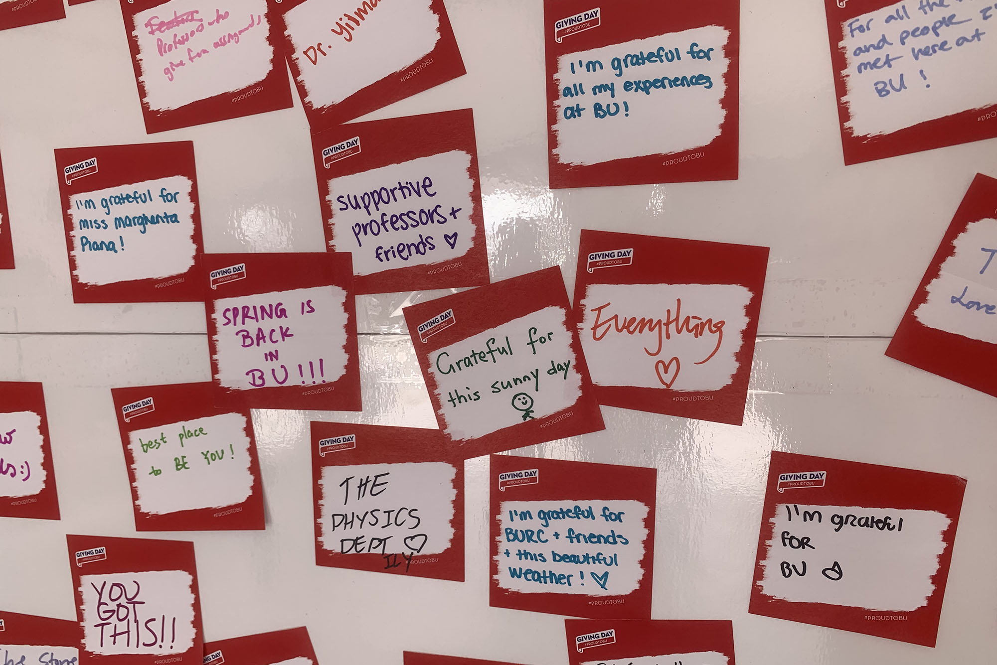 Photo: A dry-erase wall is covered in stickers that have been personalized by the BU students.The say positive quotes and/or what the students are most grateful for.