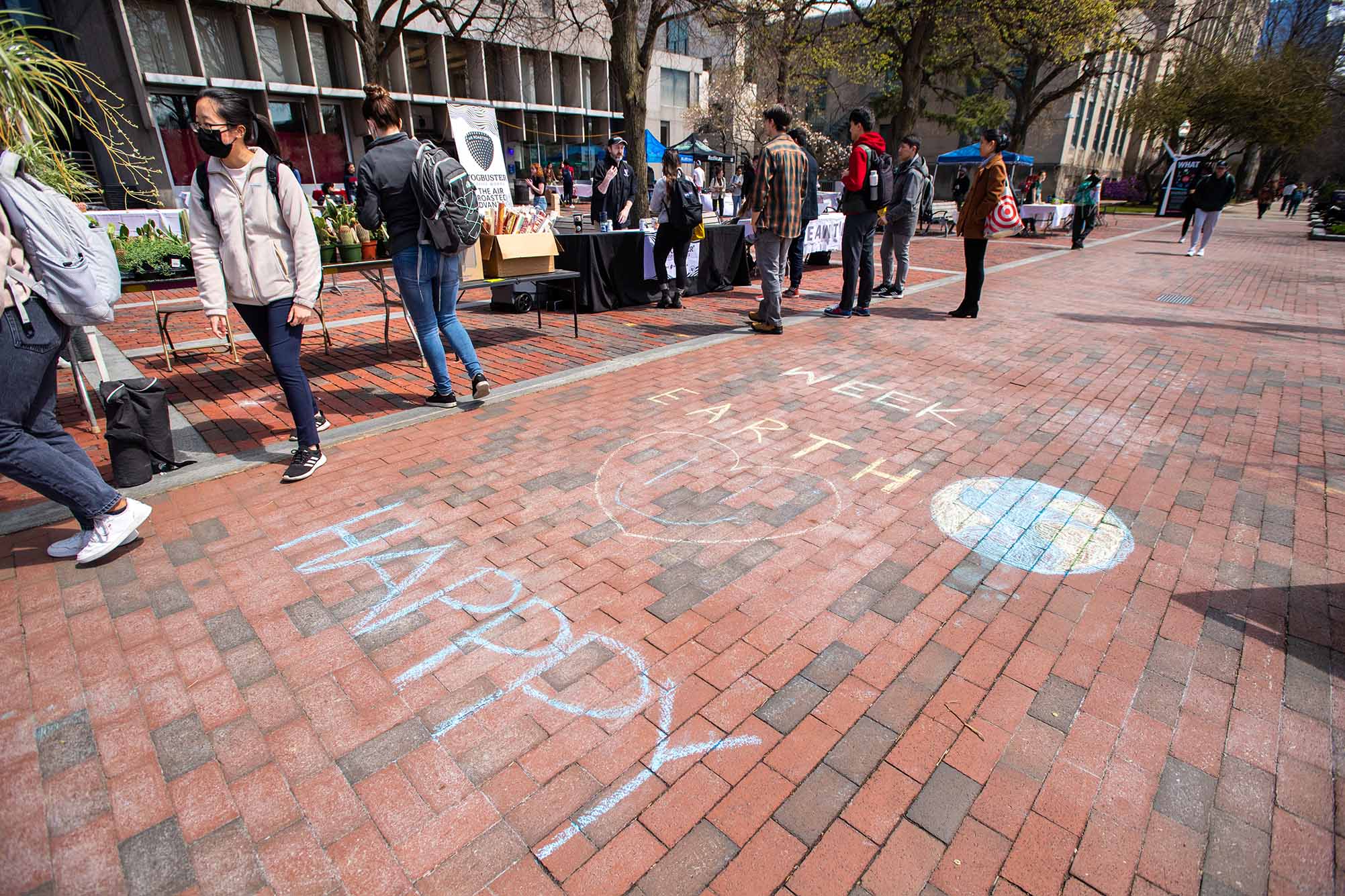 Photo: A brick sidewalk with chalk words that read "HAPPY EARTH WEEK" with a simple drawing of the Earth next to the word, earth.