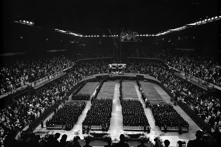 Photo: A black and white photo of a wide shot showing BU's 1961 commencement. The seniors are filing in slowly, and the audience is packed.