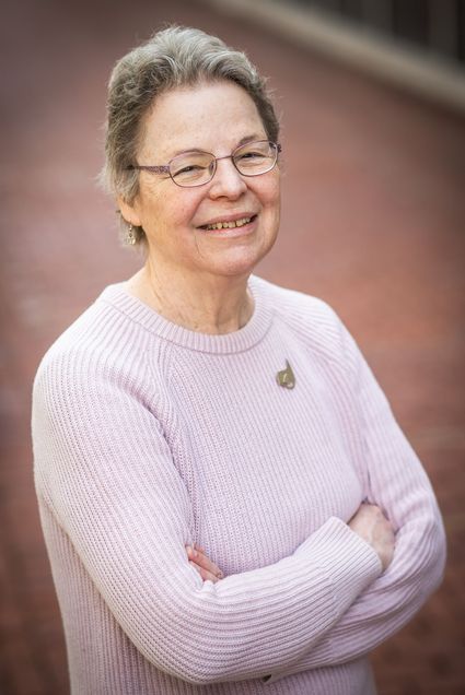 Photo: A portrait of Susan Norris, a white woman with short, gray hair, wire glasses, and a pink sweater.