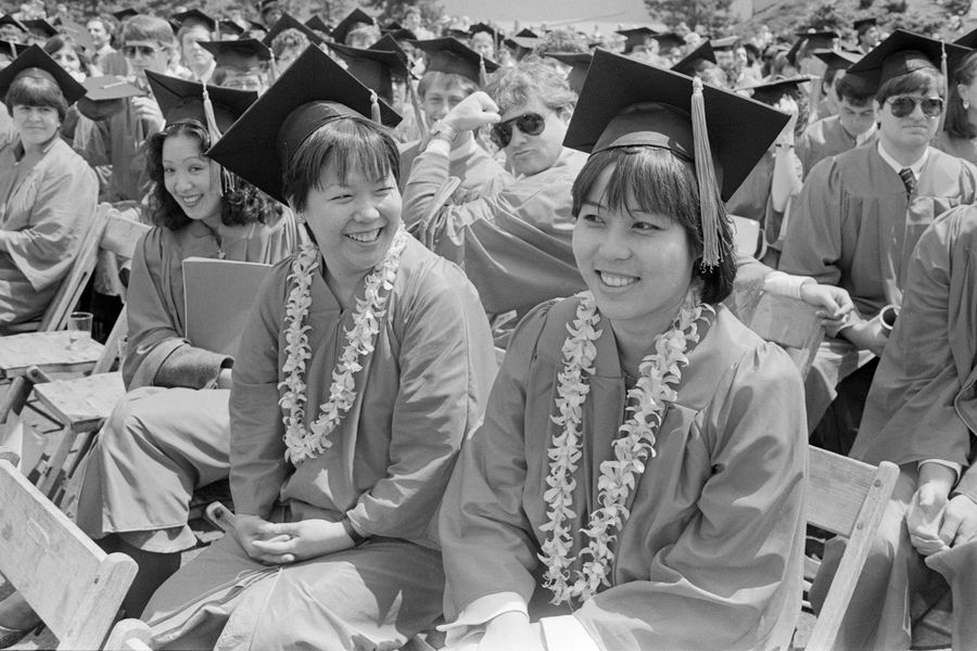Photo: Two asian graduates decorated with leis over their red robes and black mortarboards at the 1985 Boston University Commencement on Nickerson Field on May 19, 1985.