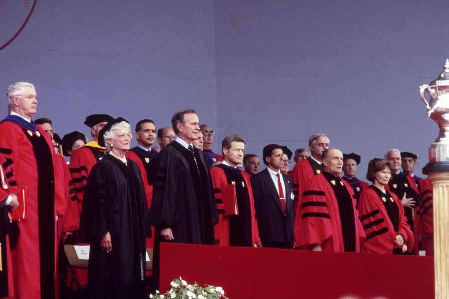 Photo: Barbara Bush, George Bush, John Silber, F. Mitterand, and others stand on the stage platform at Boston University's 1989 Commencement
